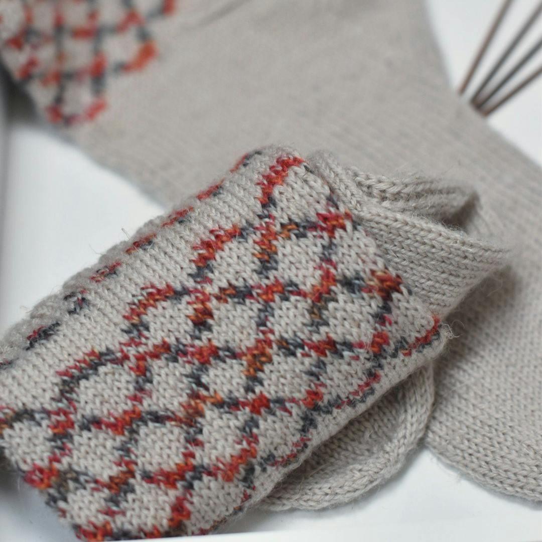 Close-up of the Dublin Memories Socks cuffs in oatmeal with rust and charcoal diamond stranded colourwork.